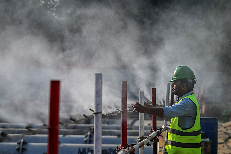 A worker adjusts an anti-smog dust suppression sprayer installed at a construction site in Lahore, Pakistan, on 17 February 2025. © Arif Ali / AFP
