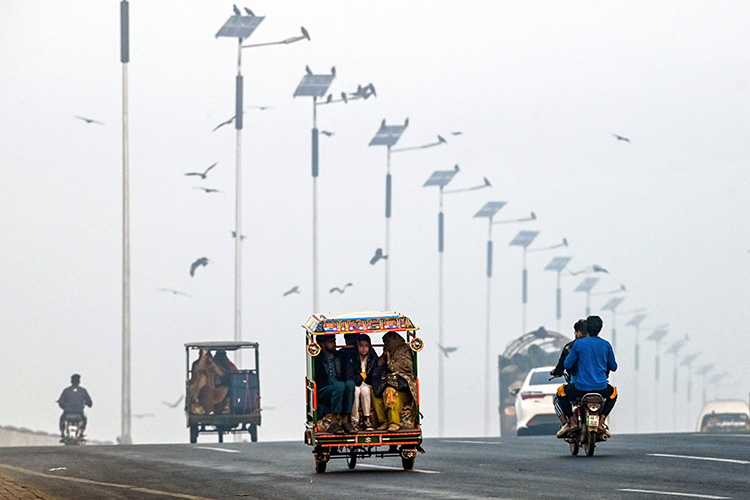 Commuters ride along a street engulfed in thick smog, in Lahore on November 20, 2024. Arif ALI / AFP
