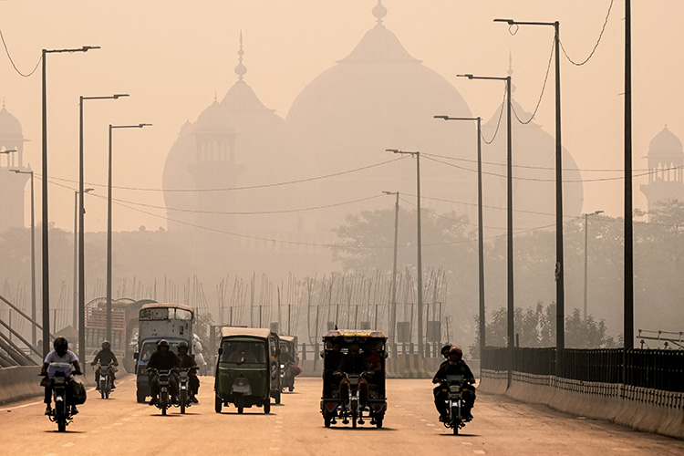 Commuters ride along a street engulfed in smog in Lahore, Pakistan, on 5 November 2024. © Arif Ali / AFP