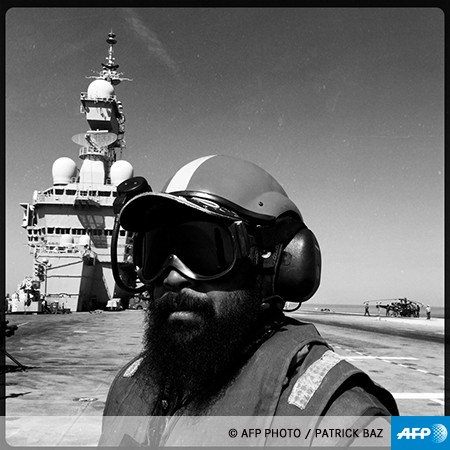 À quoi ressemble l'intimité des matelots qui font tourner le fleuron de la marine française? Comment vit-on sur cette immense forteresse flottante qui ne dort jamais? À deux reprises, le photographe de l'Agence France-Presse (et Juré du prestigieux prix World Press Photo) Patrick Baz a été amené à effectuer une mission sur ce titan des mers. À deux reprises, il a choisi de compléter son reportage traditionnel par des photos prises avec son téléphone portable. A chaque fois, il a ainsi capté des morceaux d'humanité que son matériel professionnel ne lui permettait pas d'obtenir.