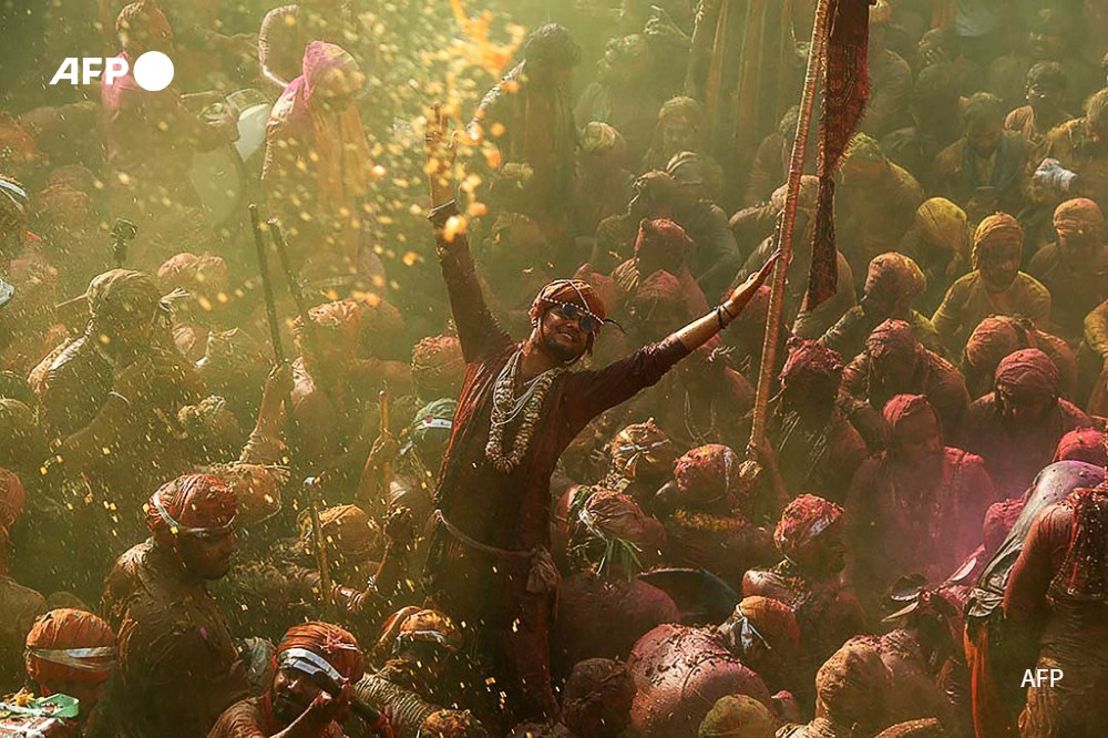 Revellers daubed in colours take part in Lathmar Holi celebrations, the Hindu spring festival of colours