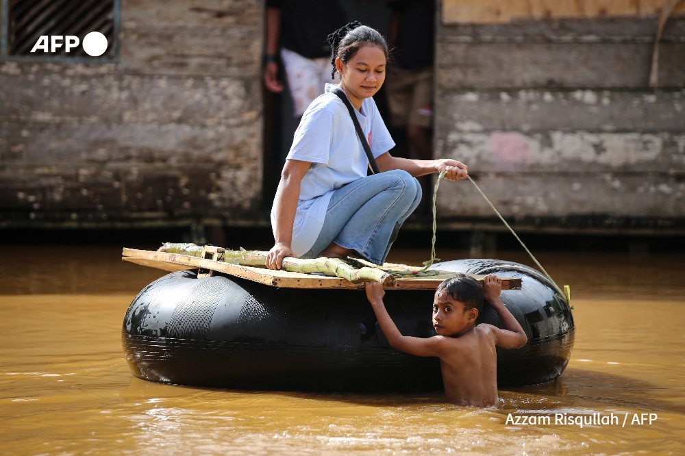 A woman rides on an inflated inner-tube in the flood affected area after the Kobe River overflowed