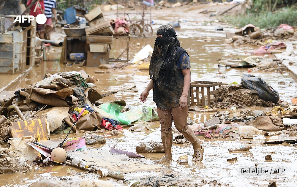 A resident walks amongst debris of destroyed belongings next to her house at a village a day after Typhoon Gaemi