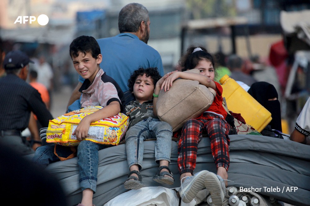 Palestinian children ride on the back of a cart with their belongings as thousands of Palestinians who fled following the Israeli army's temporary evacuation order for parts of Khan Yunis
