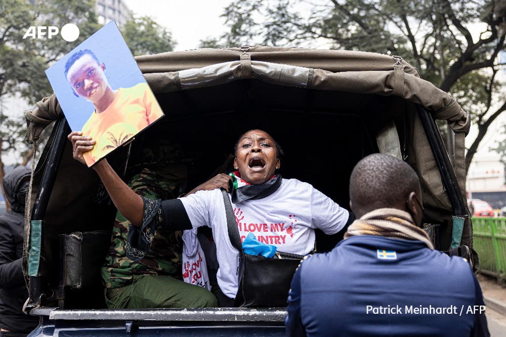 A relative of Evans Kiratu holds his picture as she gets arrested during a protest march to parliament