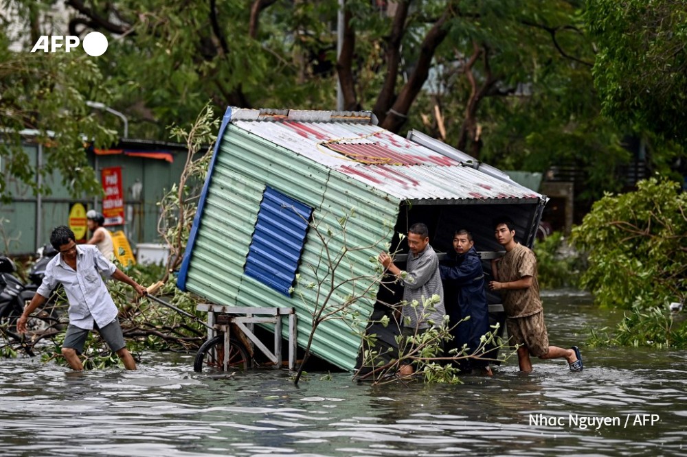 Men collect debris on a flooded street after Super Typhoon Yagi hit Hai Phong