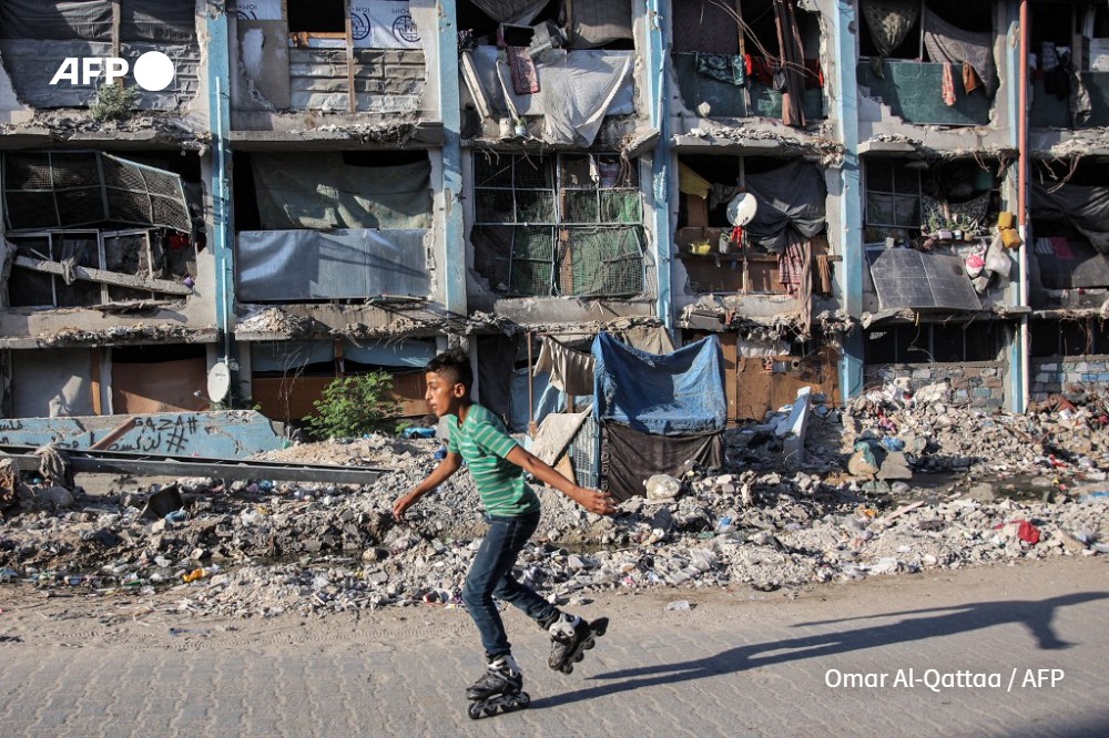 A boy roller-blades past a destroyed building at a camp sheltering people displaced by conflict in Jabalia in the northern Gaza Strip