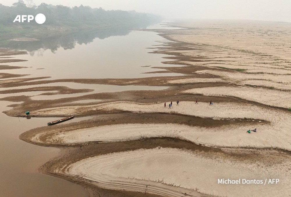People carry drinking water along a sandbank of Madeira River in Paraizinho Community, in Humaita
