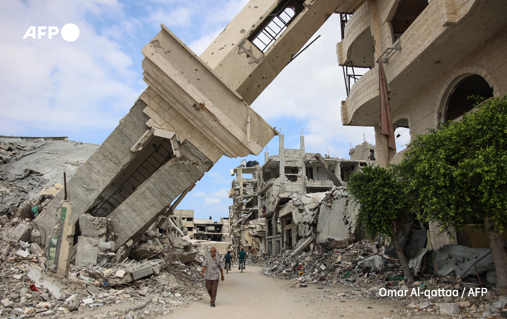 Palestinians walk beneath the tilted minaret of a destroyed mosque in the Shujaiya neighbourhood of Gaza City on October 7, 2024, on the first anniversary of the ongoing war in the Gaza Strip between Israel and the Palestinian Hamas group. 