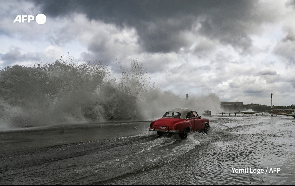An old American car drives past waves crashing against the Malecon promenade in Havana due to the passage of Hurricane Milton on October 9, 2024. 