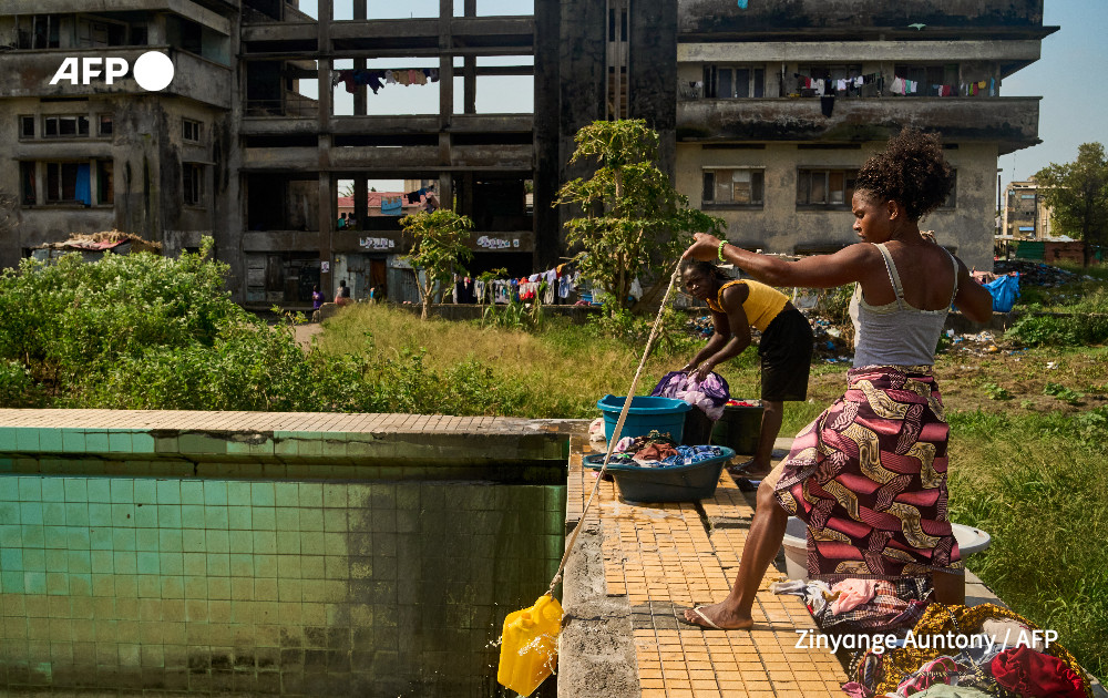 A woman uses a rope and a plastic container to get water from the Olympic size pool to wash clothes at the Grande Hotel in Beira on October 12, 2024. 