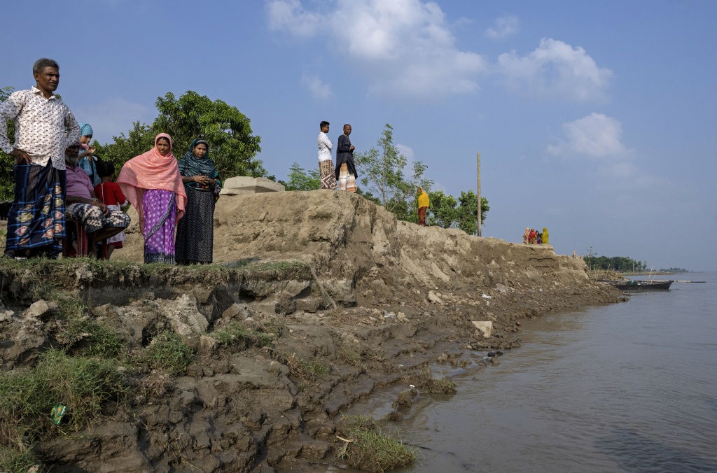 Villagers stand along the eroded Padma river embankment at Namo Jagannathpur village — Salahuddin Ahmed / AFP
