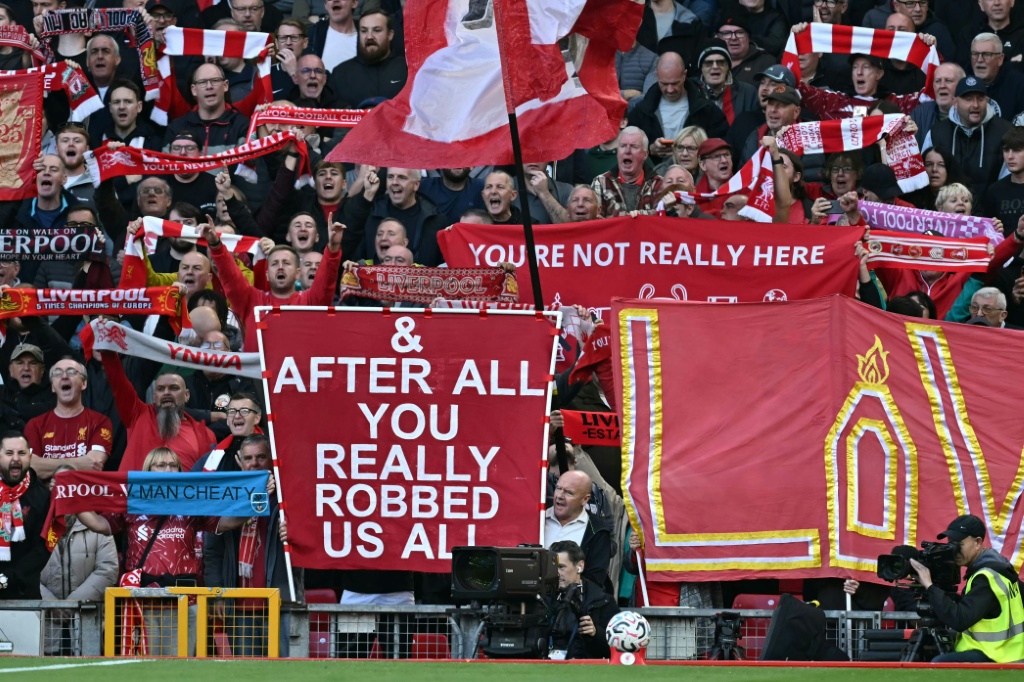 Liverpool fans hold signs mocking Manchester City's financial scandal — Paul ELLIS / AFP