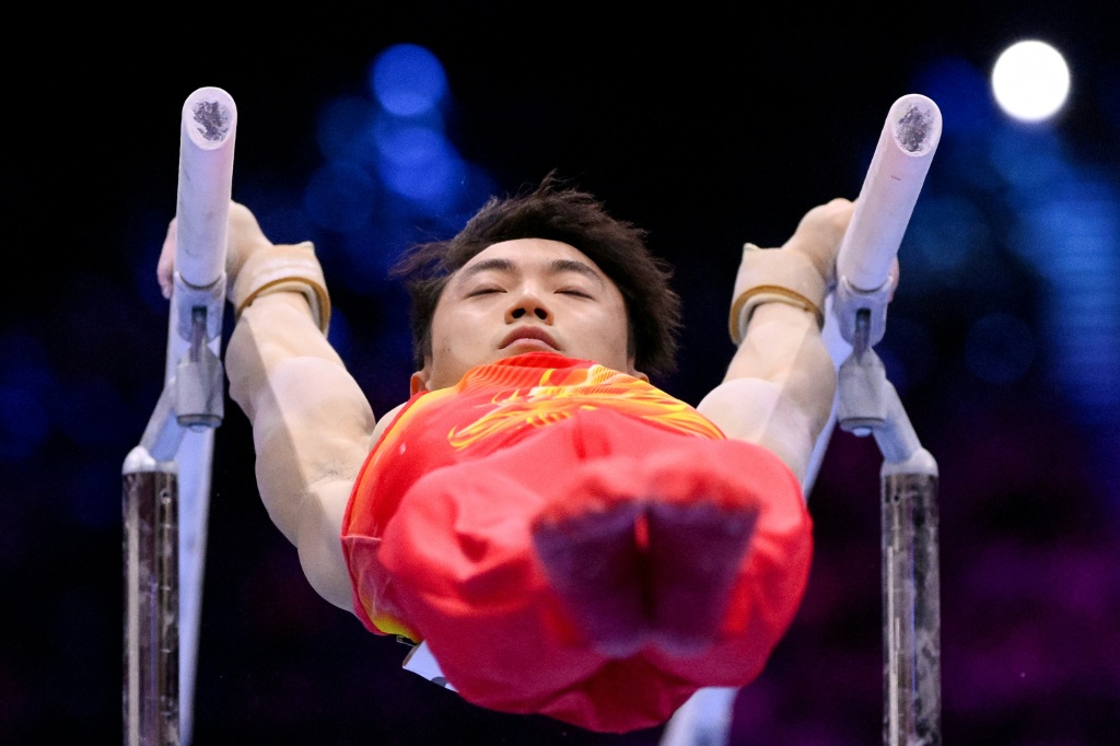 China's Jingyuan Zou swinging to the men's parallel bars world title — JOHN THYS / AFP