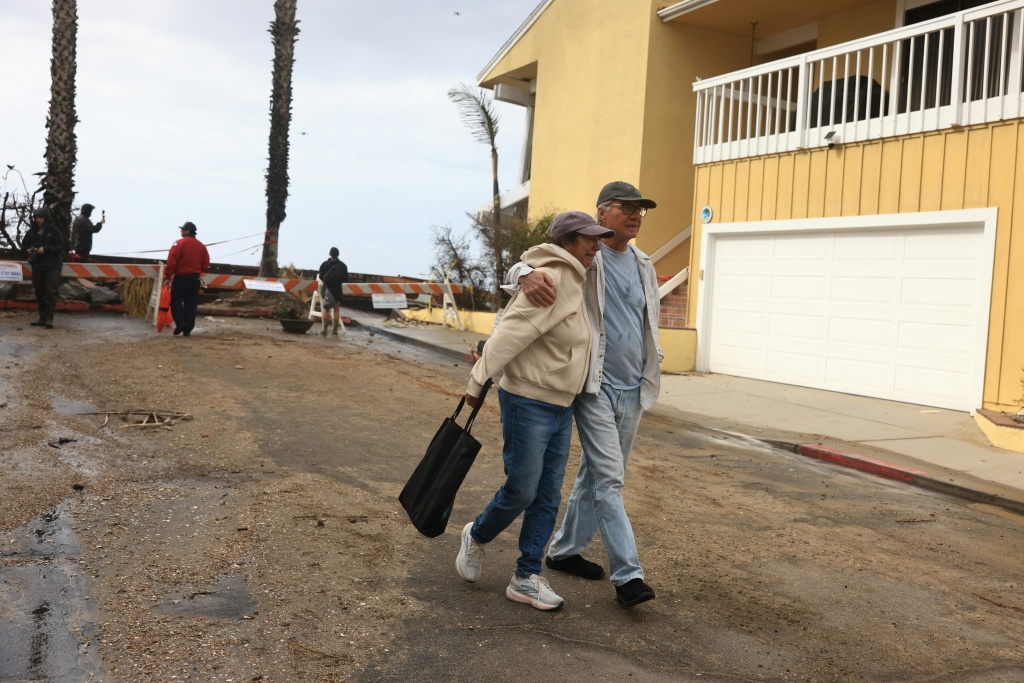 A couple react to storm damage on the boardwalk and homes created by Tropical Storm Rachel in Long Beach, California — David Swanson / AFP