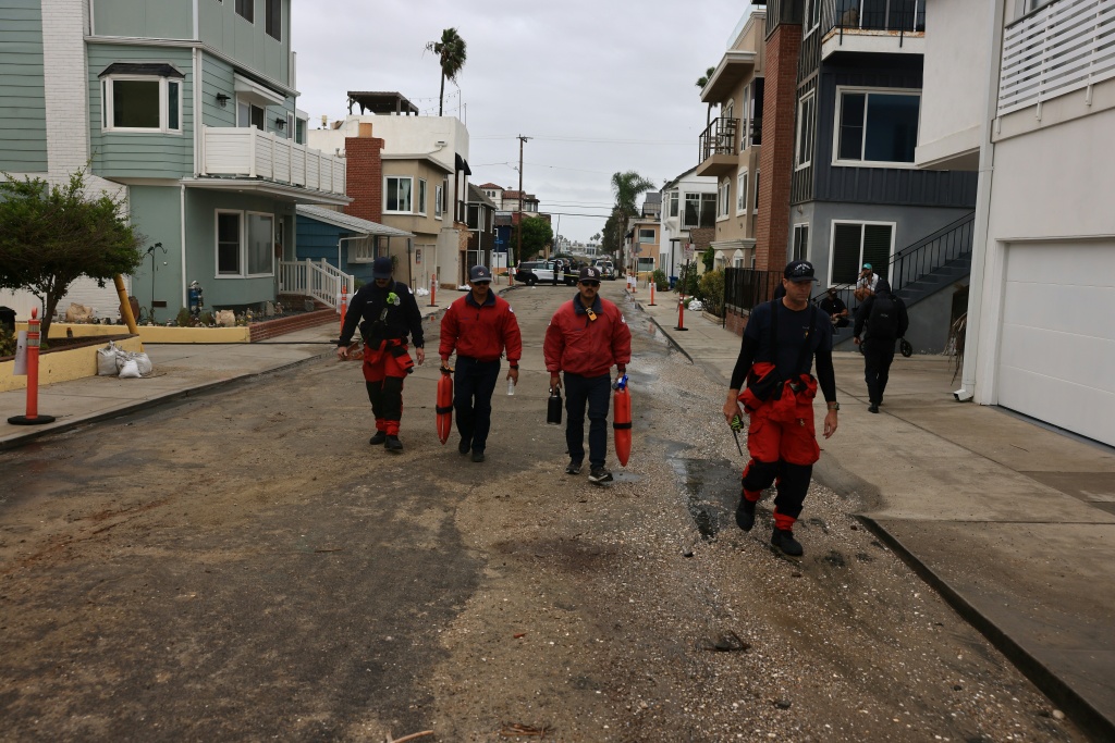 Members of the fire department inspect storm damage on the boardwalk and homes created by Tropical Storm Rachel in Long Beach, California — David Swanson / AFP