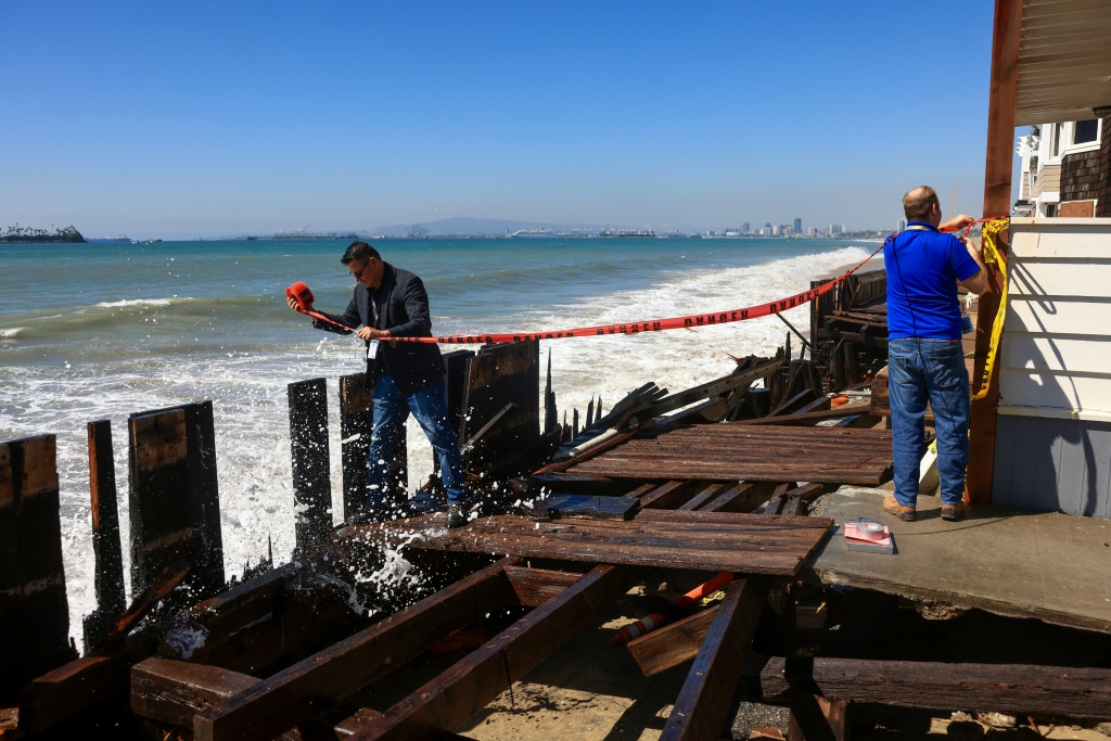 People tape off the damaged boardwalk due to the storm surge in Long Beach, California, where Tropical Storm Rachel could continue to threaten coastal flooding over the weekend — David Swanson / AFP