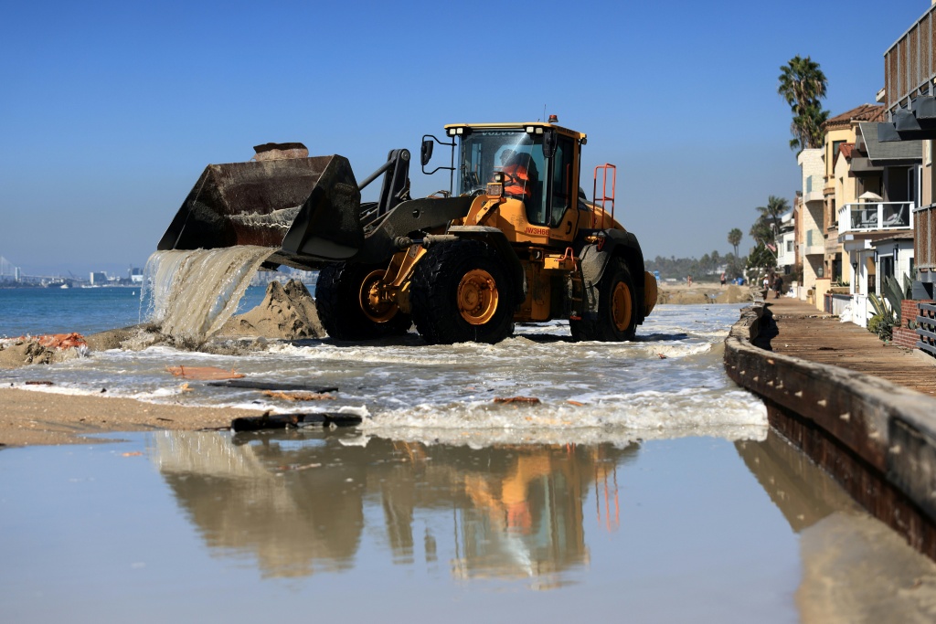 Sand and water is removed by heavy equipment outside the beachfront houses in Long Beach, California, where coastal flooding has damaged homes — David Swanson / AFP