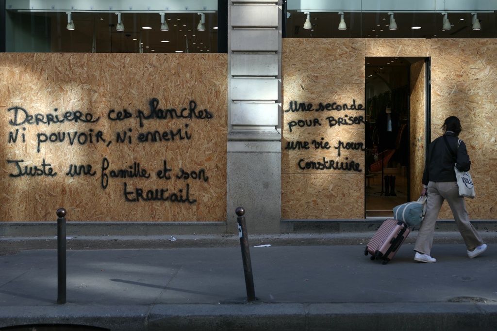 Some shopkeepers left messages on the boarded-up facades of their businesses appealing to be spared by the looters — Thomas SAMSON / AFP