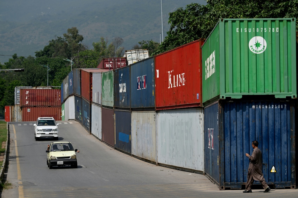 Commuters drive past shipping containers placed by authorities to block access to central Islamabad ahead of a protest by opposition party Pakistan Tehreek-e-Insaf — Aamir QURESHI / AFP