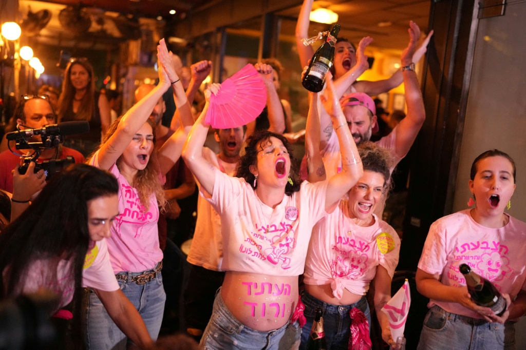 Israelis cheer at a bar after the first exit polls were announced, in Tel Aviv — MAYA LEVIN / AFP