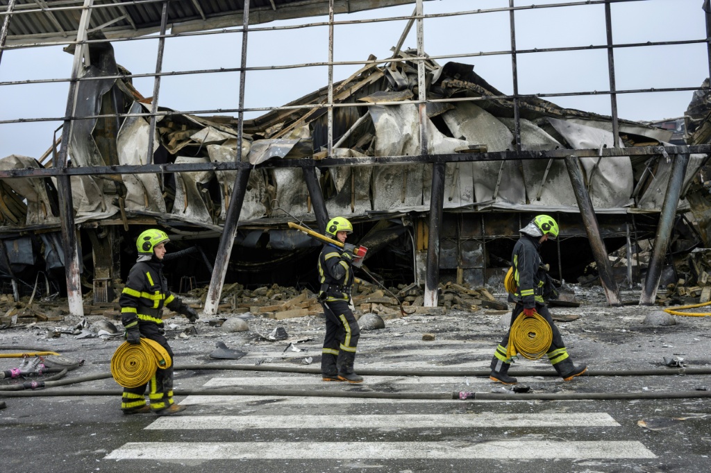 Ukrainian rescuers walk at the site of a shopping centre damaged following a missile strike in Kyiv — Vladislav MUSIENKO / AFP