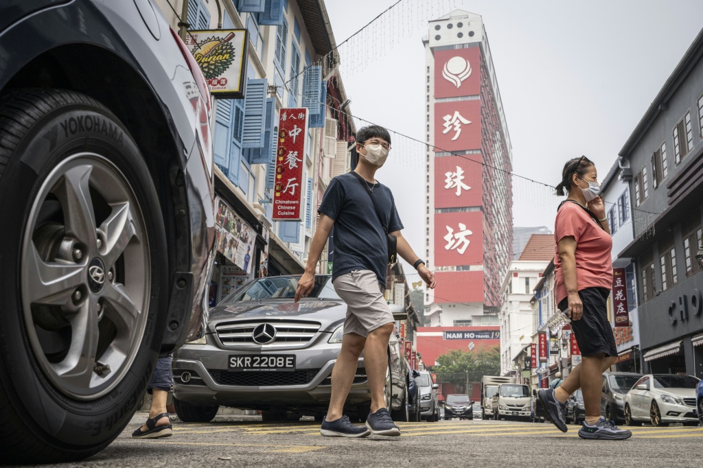 People wearing face masks cross a street in Singapore's Chinatown on  as the country continues to be shrouded in haze caused by fires in Indonesia — Yuichi YAMAZAKI / AFP