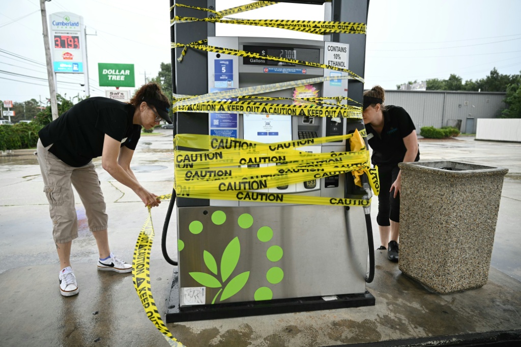 Workers cordon off a gas pump with yellow tape at a gas station in Navarre, Florida as Hurricane Isaias approaches — RONALDO SCHEMIDT / AFP