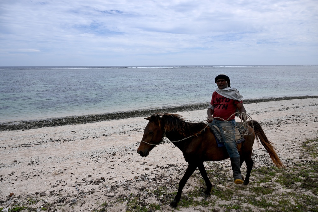 This picture taken on October 5, 2026, shows a villager riding a horse along the beach in the Naidiri Marine Biodiversity Park, a marine protected area about 52 kilometres from Nadi. Climate change is threatening the livelihoods of coastal communities in Fiji, with coral bleaching and habitat loss contributing to dwindling fish stocks. — Saeed KHAN / AFP