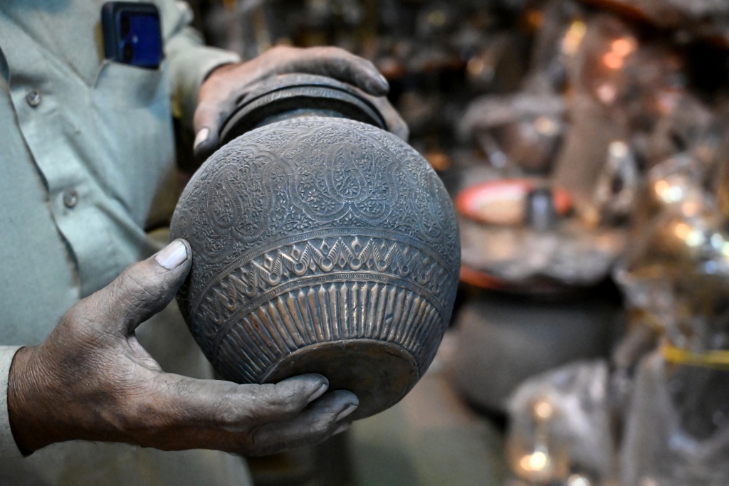 Antique dealer Ahsan Shakeel shows an artefact at his shop selling vintage items in Rawalpindi — Farooq NAEEM / AFP