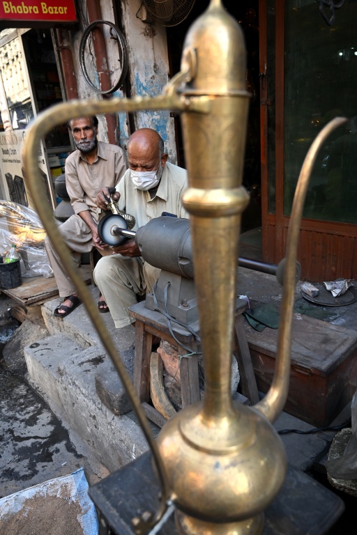 Antique dealer Ahsan Shakeel polishes an artefact outside his shop selling vintage items in Rawalpindi — Farooq NAEEM / AFP