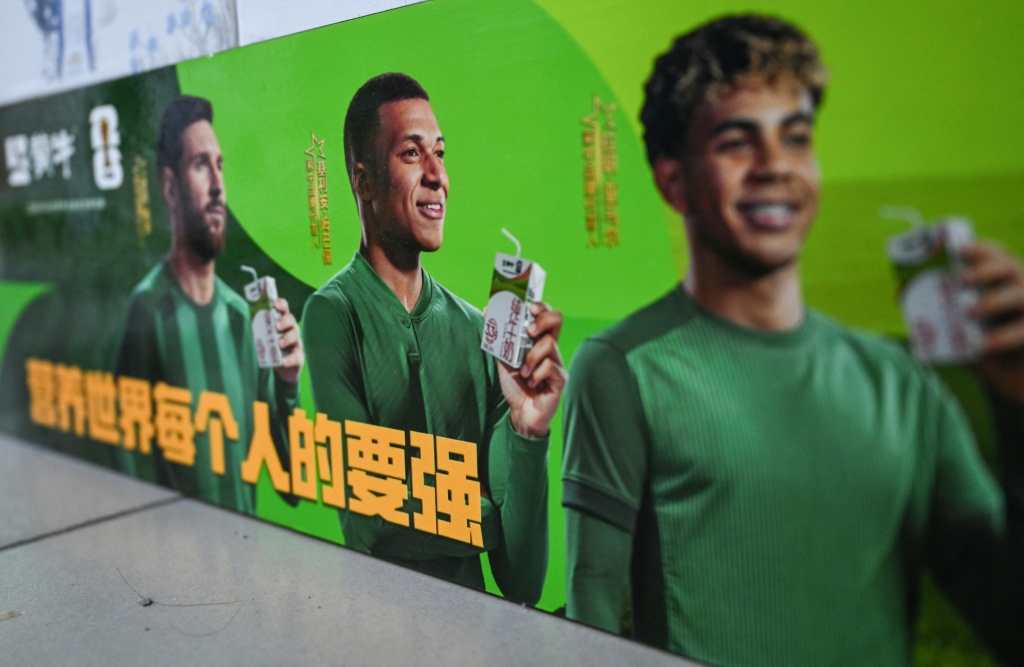 People walk past a bus featuring French football star Kylian Mbappe — Jade GAO / AFP