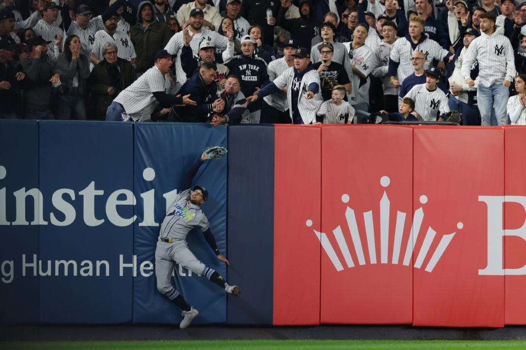 Victor Mesa Jr. of the Tampa Bay Rays is unable to make a catch as fans interfere on a ball hit by Anthony Volpe of the New York Yankees — Caleb Bowlin