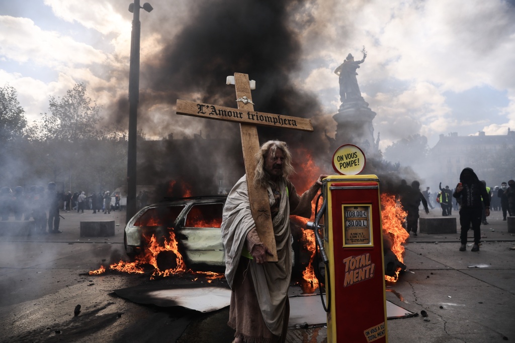 A protester with a cross stands next to an effigy of a gasoline pump in Paris — Kiran RIDLEY / AFP