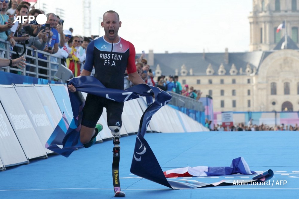 France's Jules Ribstein celebrates as he crosses the finish line to win the men's PTS2 para triathlon event at the Paris 2024 Paralympic Games at the Pont Alexandre III on September 2, 2024.
