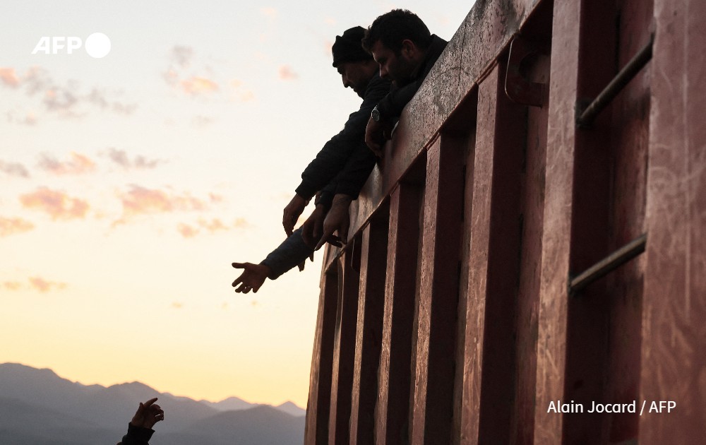 Refugees stand in the back of a truck