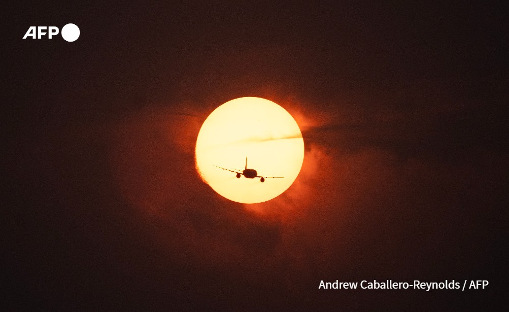 A plane passes in front of the sun