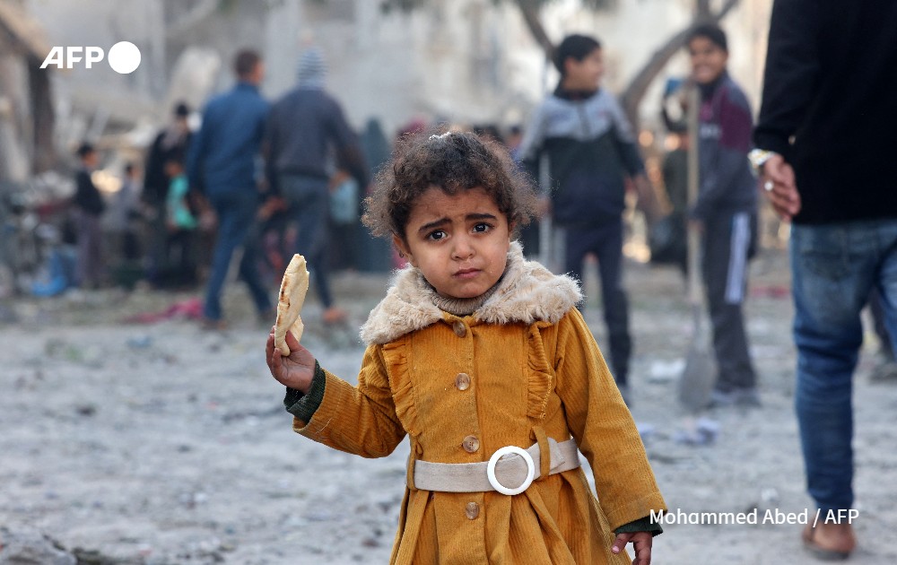 A Palestinian girl eats a piece of bread
