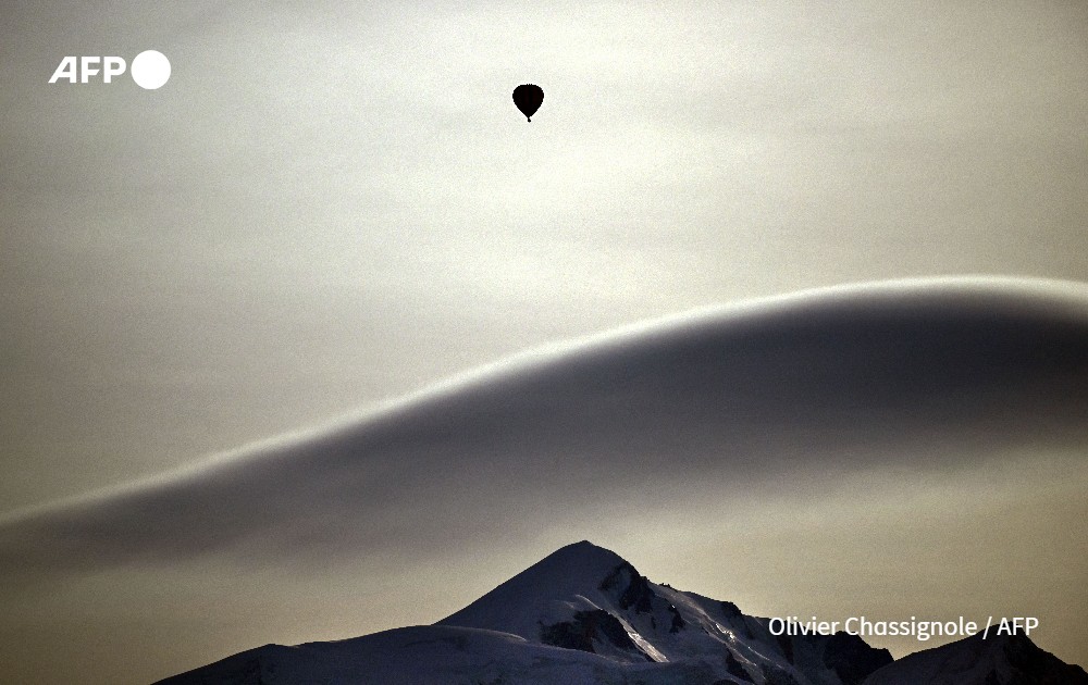 A hot air balloon drifing over the Massif du Mont-Blanc mountains