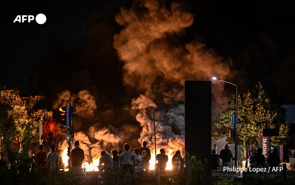 People look at burning tyres blocking a street in Bordeaux