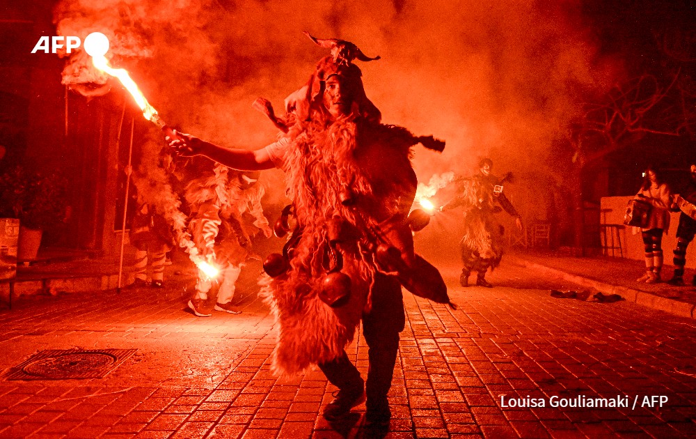 Costumed reveller lights a flare during carnival in Greece