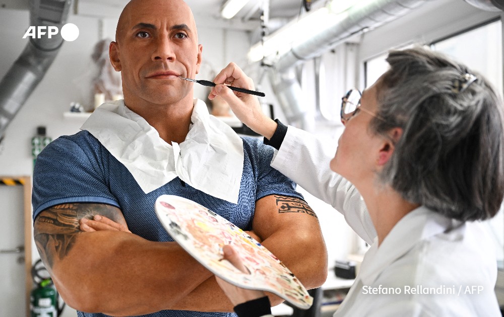 Employee adjusts the skin tone on the wax effigy of Dwayne Johnson