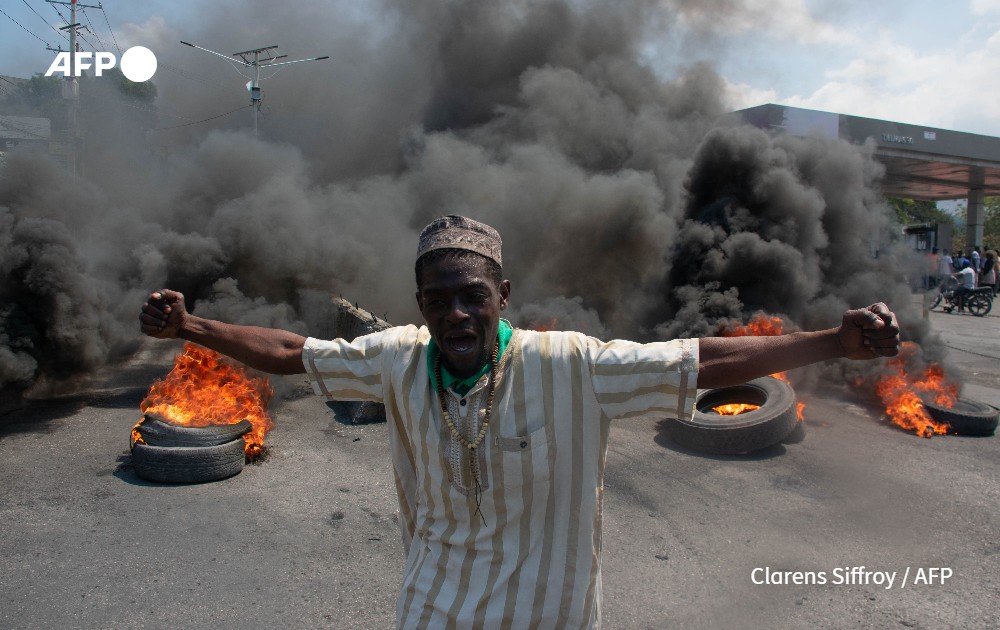A protester reacts while tires burn in the street during a demonstration