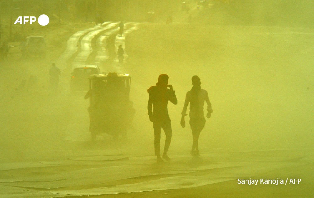 People commute along a road during a sand storm