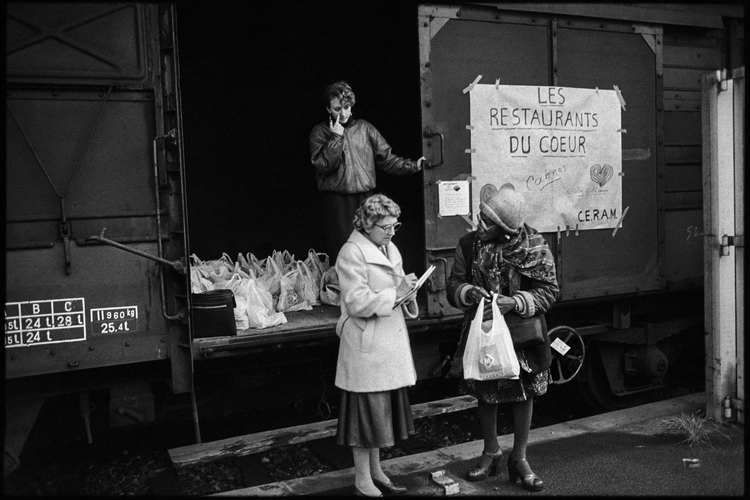 Volunteers from the Restaurants du Coeur distribute bags of food from a SNCF train wagon in Cannes on December 29, 1985.