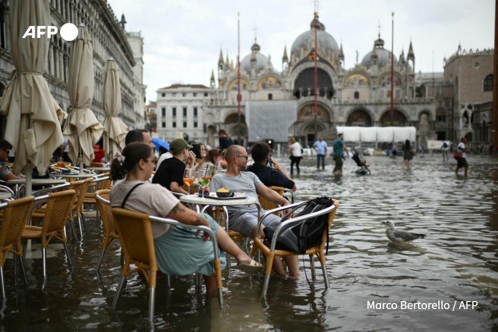 People stay at cafe terrace in a flooded St. Mark's square during high tide (aqua alta) on September 5, 2024 in Venice.
