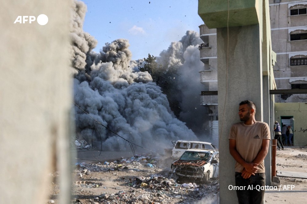 A man takes cover behind a column as an explosion propagates smoke and dust during an Israeli strike which reportedly targeted a school in the Zeitoun district on the outskirts of Gaza City, on September 1, 2024, amid the ongoing conflict between Israel and the Palestinian Hamas group.