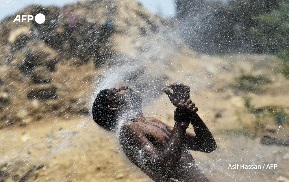 A man cools off from a water supply leakage, Pakistan