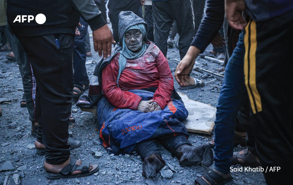 Woman injured in an Israeli strike sits amid the rubble