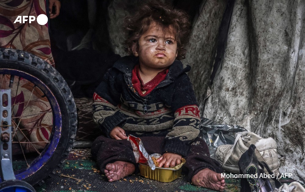 A Palestinian child eats food from a box